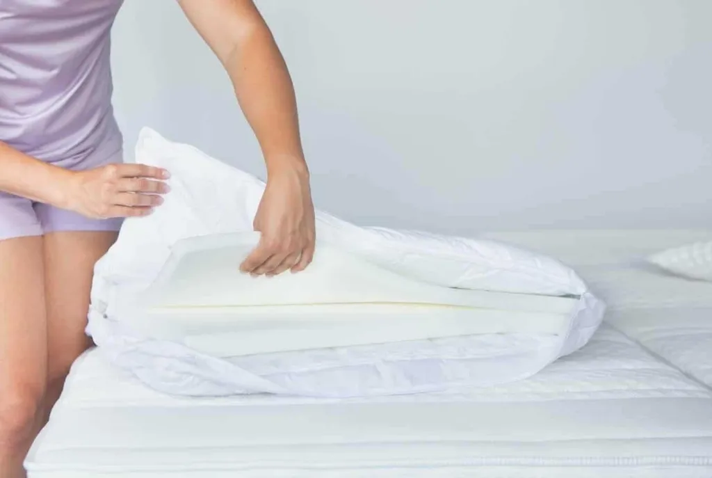 Selection by Bico Kissen ClimaLuxe Vario Frau steht neben Matratze und haelt das Kissen offen Einlagen